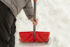 Man with a snow shovel near the snow pile