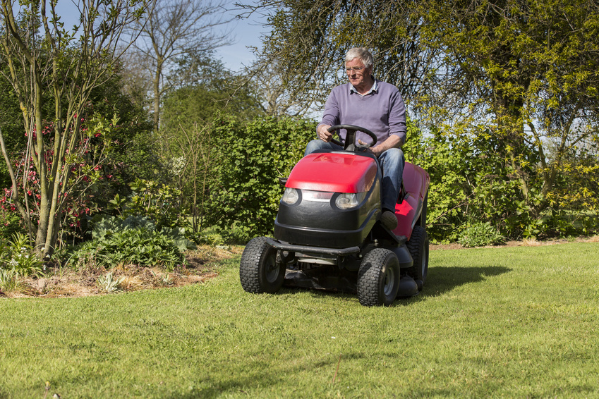 senior gardener mowing the lawn with tractor France