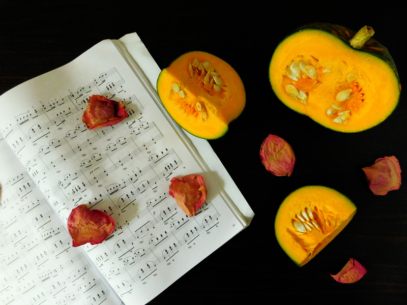 Romantic autumn composition made of pumpkin, song book and dried rose petals