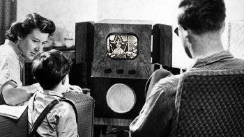 A black-and-white image of a 1950s family watching Queen Elizabeth II's Coronation on a valve television with a tiny screen.