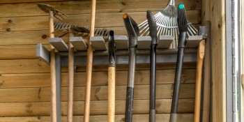 A rack of wall-mounted tools in a garden shed.